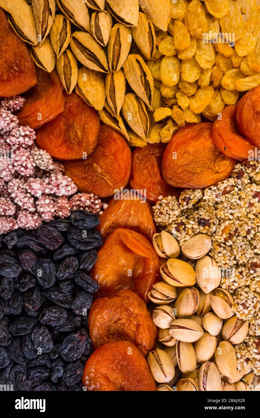 Verschiedene Nüsse und Trockenfrüchte, Aprikosen, Rosinen, Sesam in runder Form auf Betongrund, Zink, Eisen, Magnesium, Mangan, phosphorreiche Lebensmittel Stockfoto