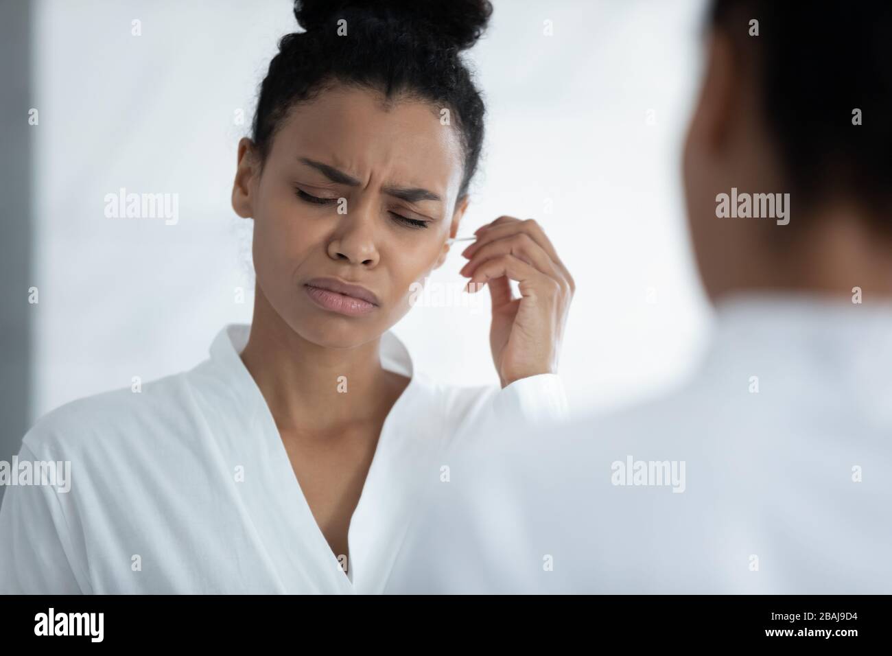 Bei der Reinigung von Ohren durch Afrikanerin wird Ohrenschmalz als Unbehagen und Schmerzen empfunden Stockfoto