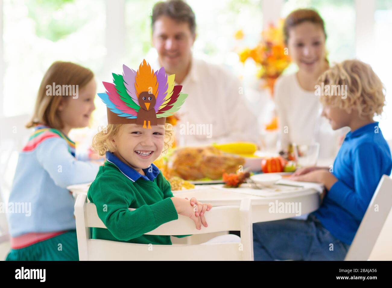 Familie mit Kindern, die Thanksgiving Abendessen essen. Geröstete truthahn- und Kürbiskuchen auf Esstisch mit Herbstdekoration. Festliche Mahlzeit für Eltern und Kinder. Stockfoto
