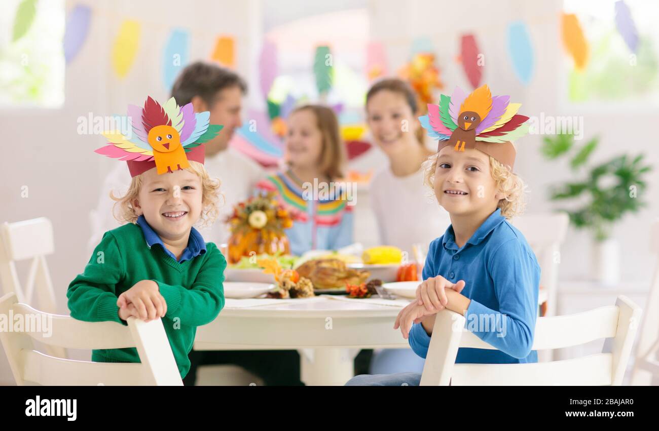 Familie mit Kindern, die Thanksgiving Abendessen essen. Geröstete truthahn- und Kürbiskuchen auf Esstisch mit Herbstdekoration. Festliche Mahlzeit für Eltern und Kinder. Stockfoto