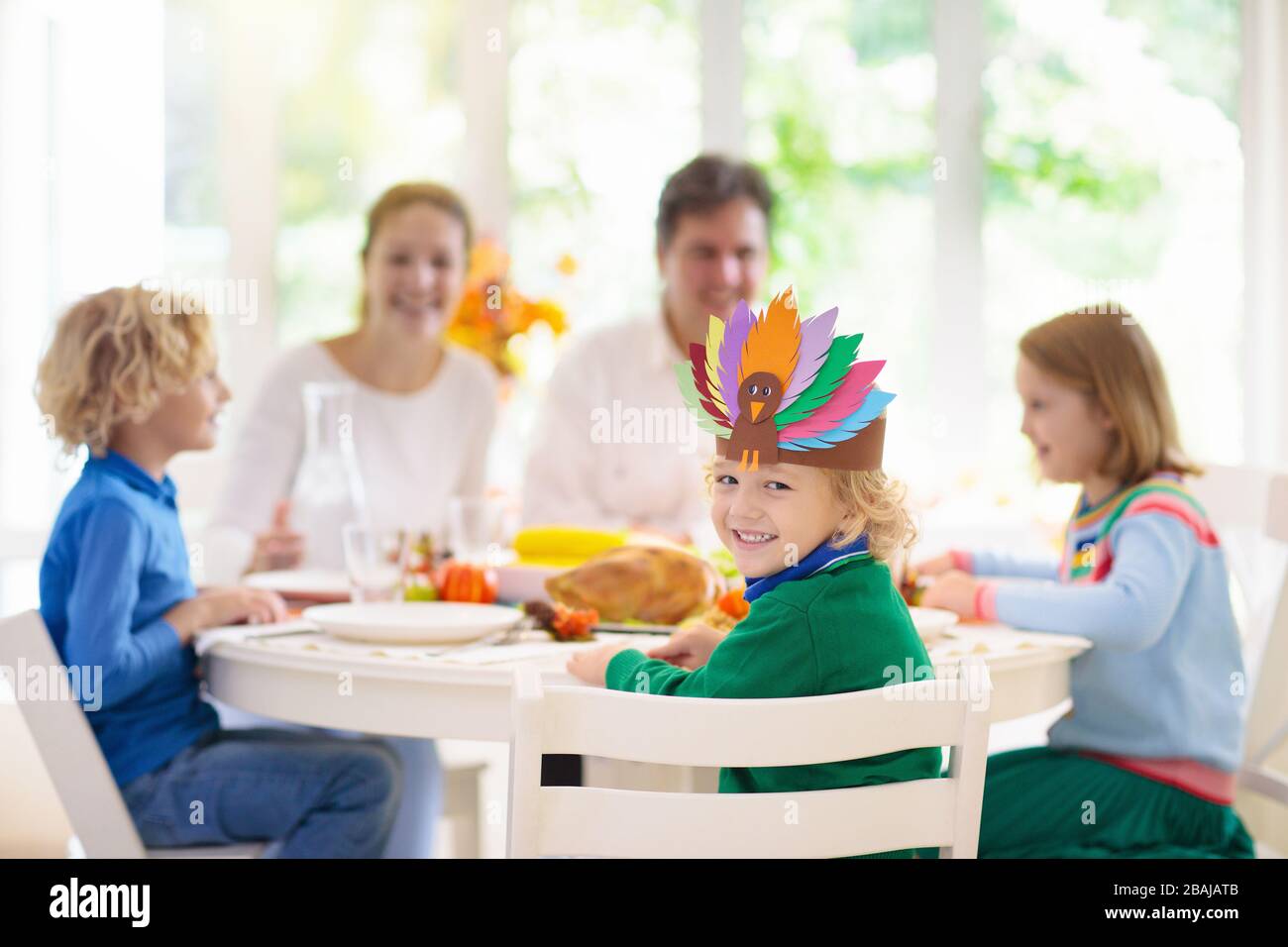Familie mit Kindern, die Thanksgiving Abendessen essen. Geröstete truthahn- und Kürbiskuchen auf Esstisch mit Herbstdekoration. Festliche Mahlzeit für Eltern und Kinder. Stockfoto