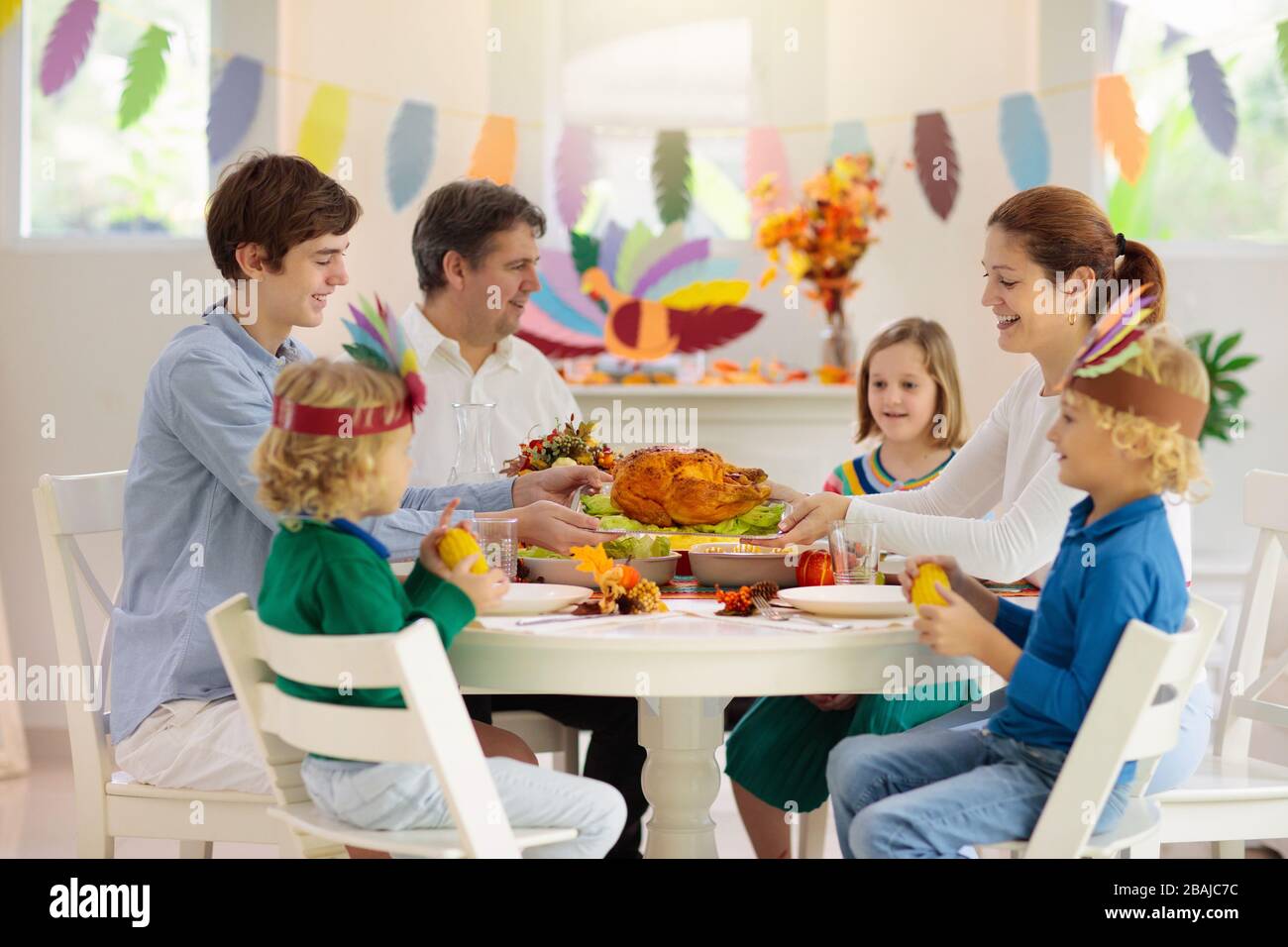 Familie mit Kindern, die Thanksgiving Abendessen essen. Geröstete truthahn- und Kürbiskuchen auf Esstisch mit Herbstdekoration. Festliche Mahlzeit für Eltern und Kinder. Stockfoto