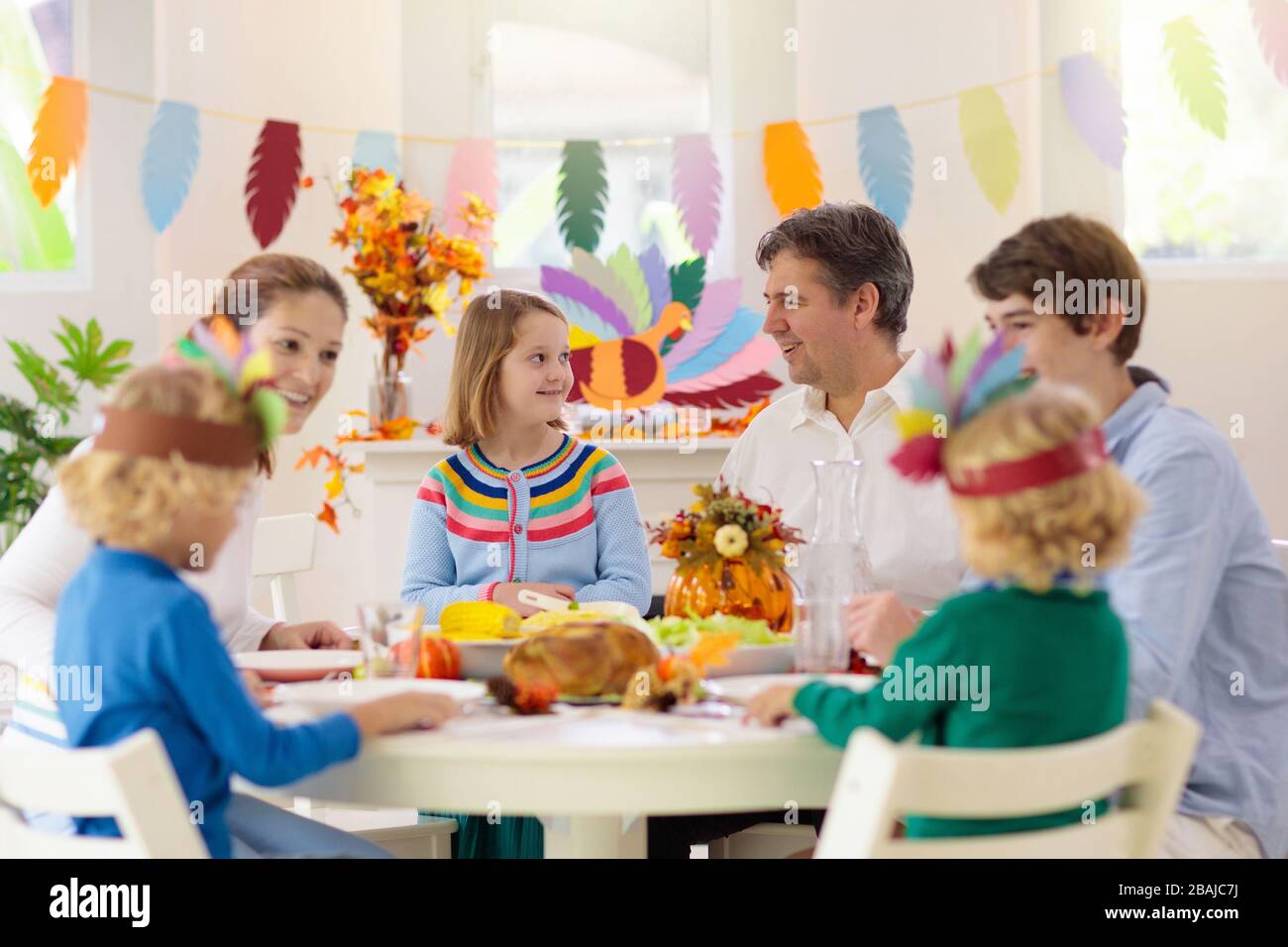 Familie mit Kindern, die Thanksgiving Abendessen essen. Geröstete truthahn- und Kürbiskuchen auf Esstisch mit Herbstdekoration. Festliche Mahlzeit für Eltern und Kinder. Stockfoto