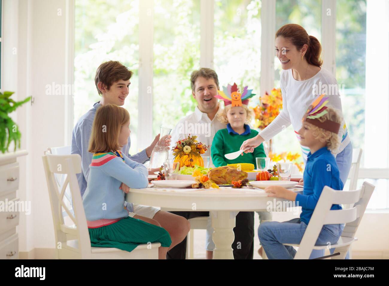 Familie mit Kindern, die Thanksgiving Abendessen essen. Geröstete truthahn- und Kürbiskuchen auf Esstisch mit Herbstdekoration. Festliche Mahlzeit für Eltern und Kinder. Stockfoto