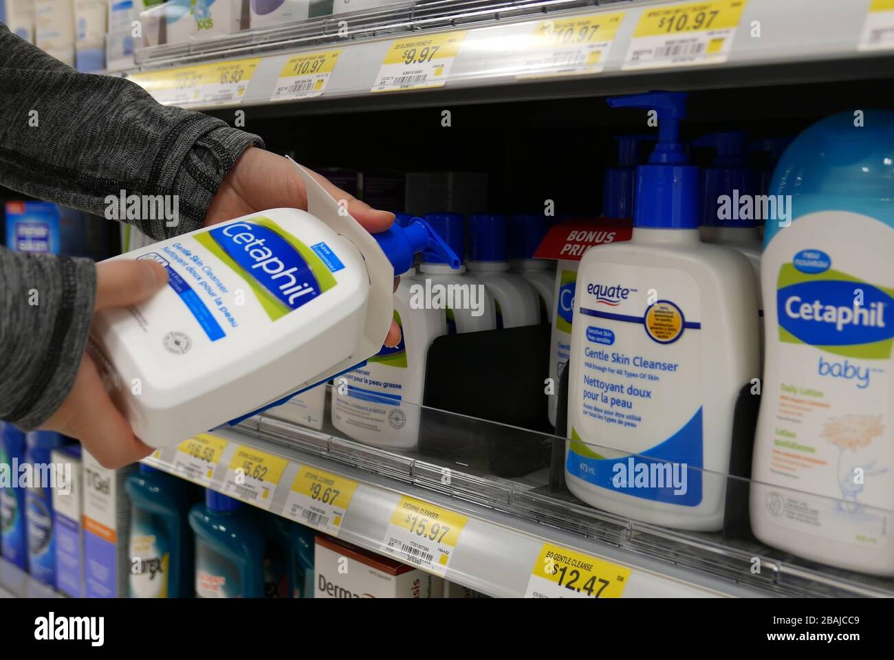 Frau, die Cetaphil sanfte Hautreinigerin im Walmart-Laden nimmt Stockfoto