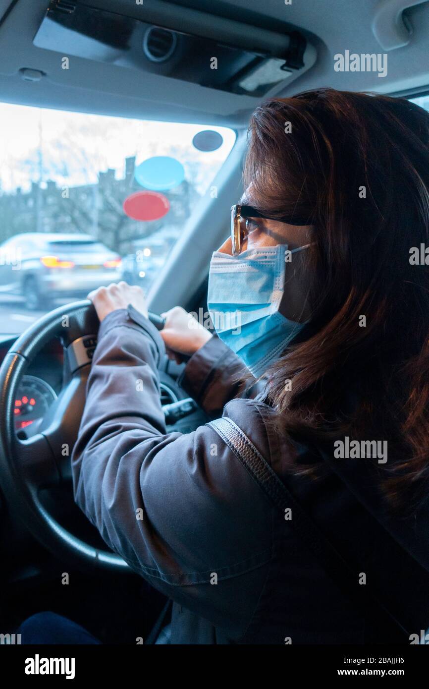 Eine Frau, die während der Fahrt eine Gesichtsmaske trägt Stockfoto