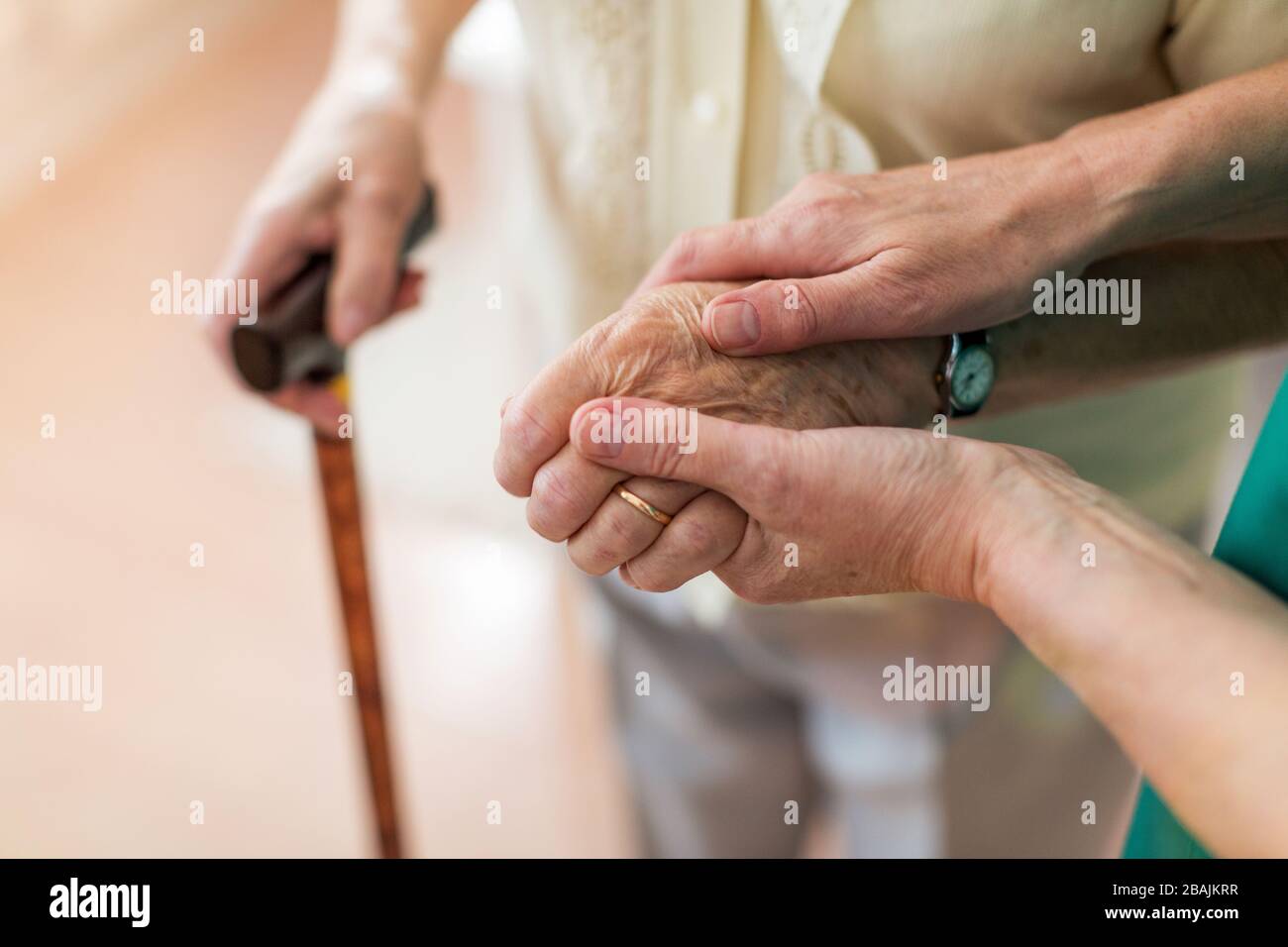 Krankenschwester tröstet ihre ältere Patientin, indem sie ihre Hände hält Stockfoto