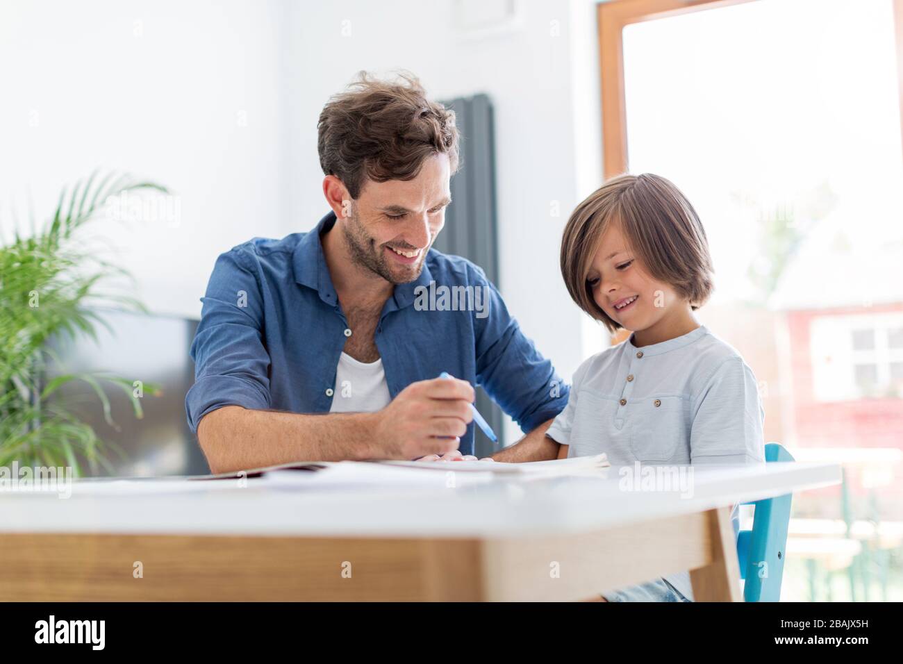 Vater und Sohn gemeinsam Hausaufgaben zu machen wie zu Hause. Stockfoto