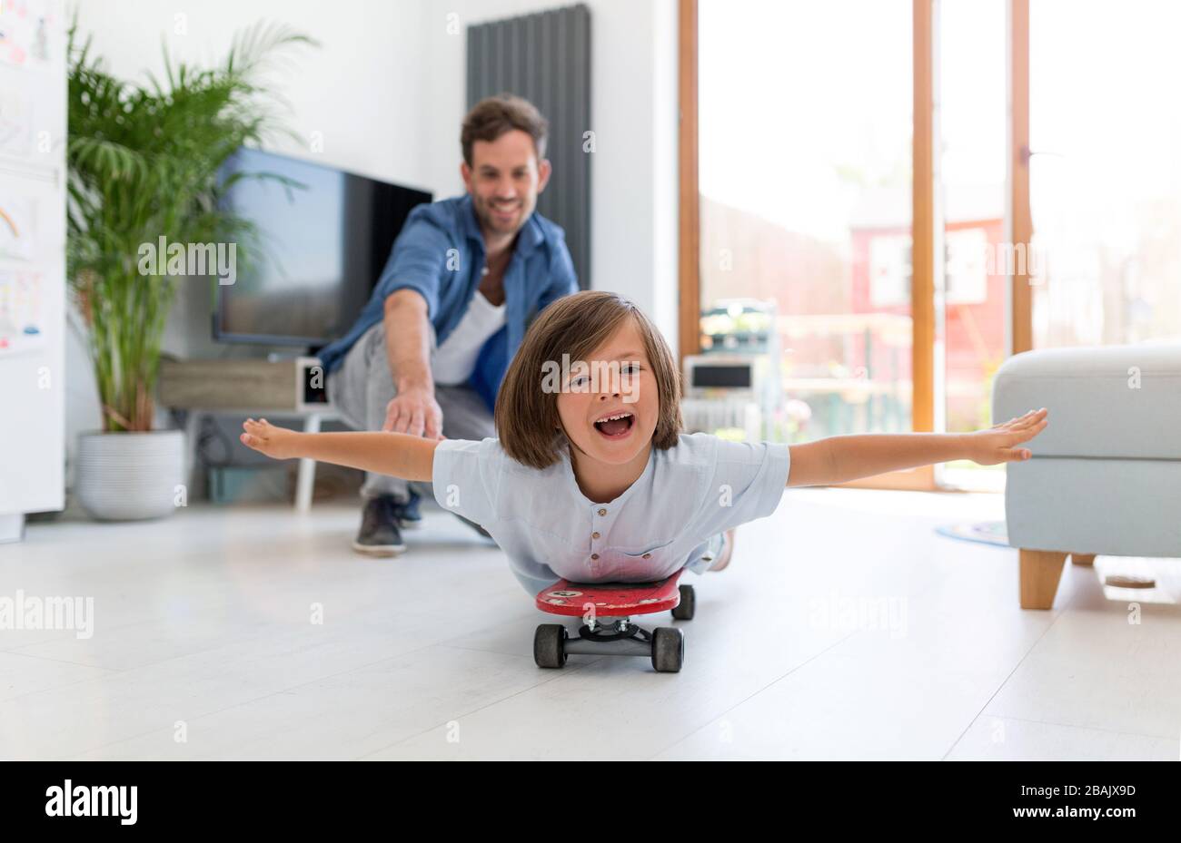 Vater schiebt Sohn auf Skateboard Stockfoto