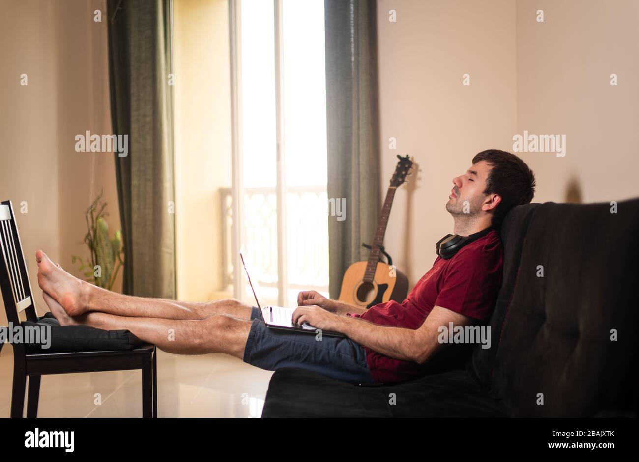 Mann, der beim Arbeiten von zu Hause auf dem Sofa napp nimmt Stockfoto