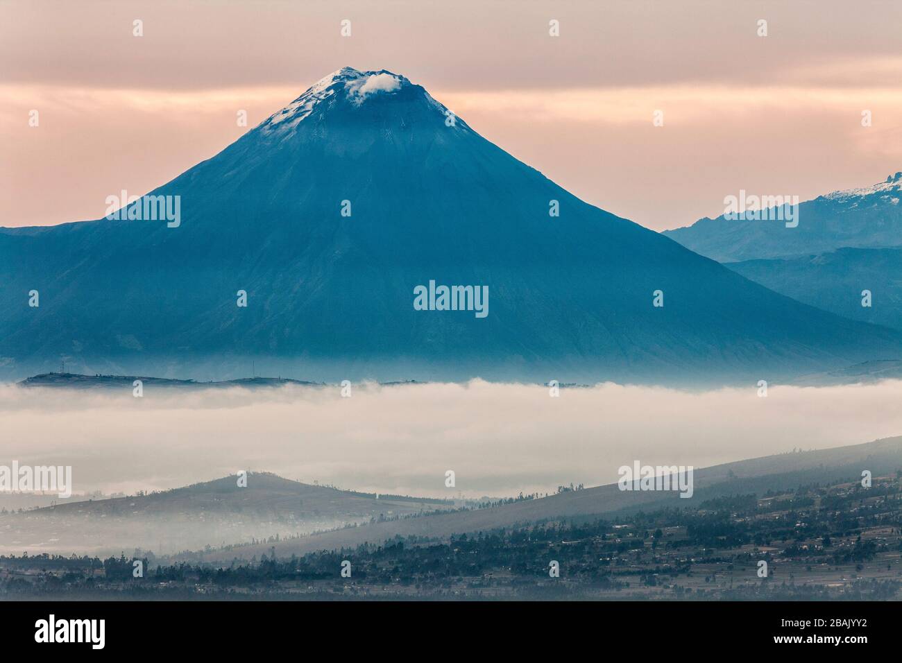 Tungurahua Vulkan bei Sonnenaufgang mit nebeligem Tal von Latacunga, Ecuador Stockfoto