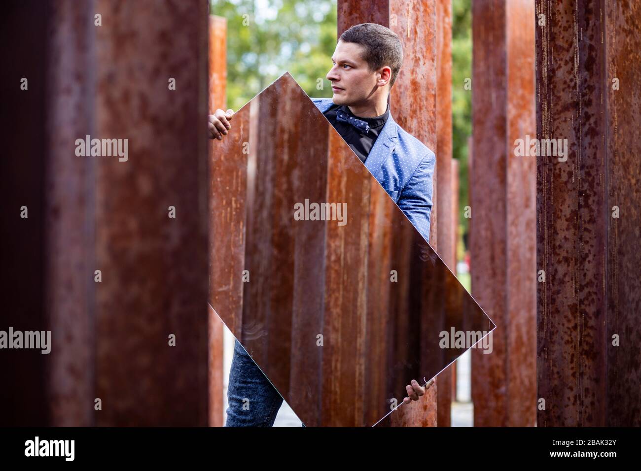 Porträt eines jungen männlichen Athleten in elegantem, stilvollem Outfit unter rohen, rostigen Eisenpfosten Stockfoto