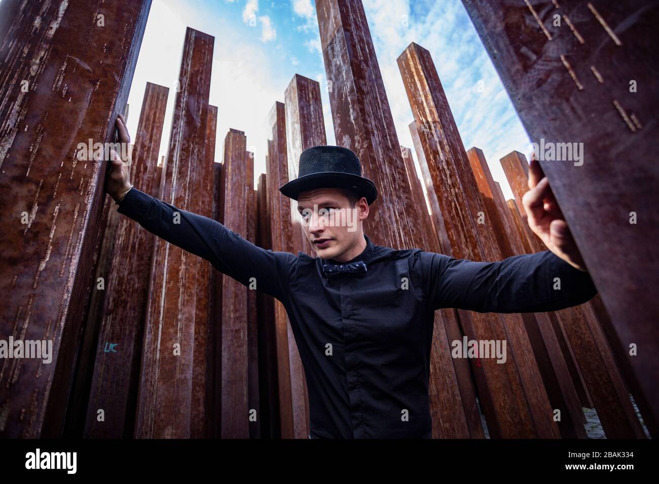 Porträt eines jungen männlichen Athleten in elegantem, stilvollem Outfit unter rohen, rostigen Eisenpfosten Stockfoto
