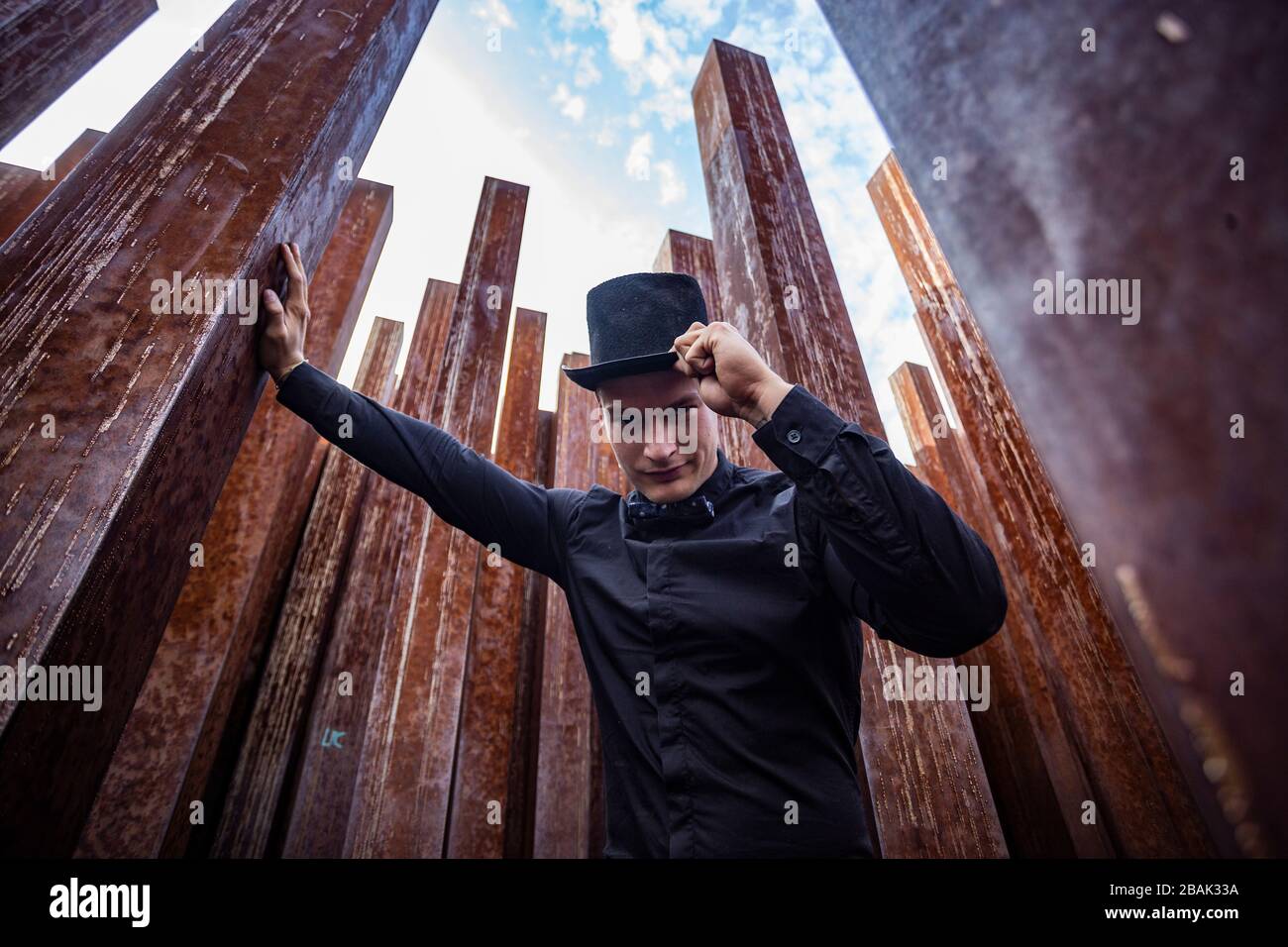 Porträt eines jungen männlichen Athleten in elegantem, stilvollem Outfit unter rohen, rostigen Eisenpfosten Stockfoto