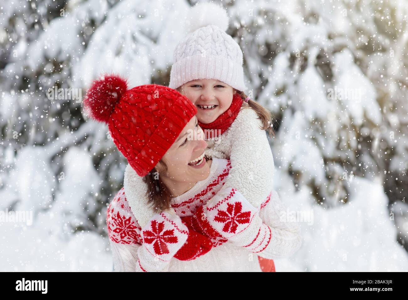 Mutter und Kind auf gestrickte Winter Mützen Spielen im Schnee an Weihnachten mit der Familie Urlaub. Handgemachte wolle Hut und Schal für Mutter und Kind. Stricken für Kinder. Kni Stockfoto