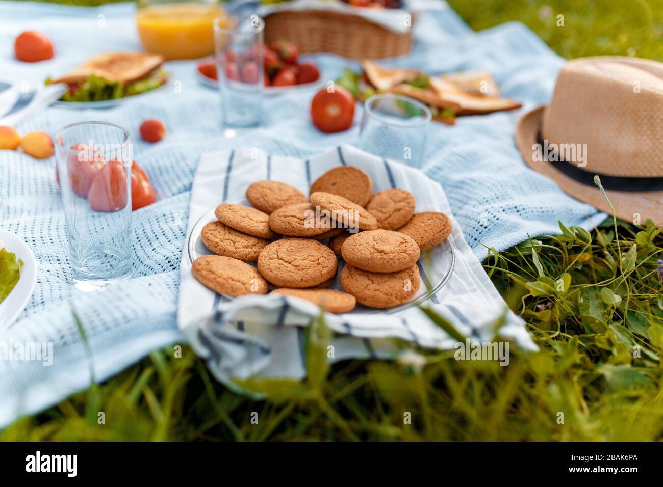 Sommerpicknick auf dem Gras mit einem offenen Picknickkorb, Obst, mit getoasteten Sandwiches und Beeren. Picknicktablecke Stockfoto