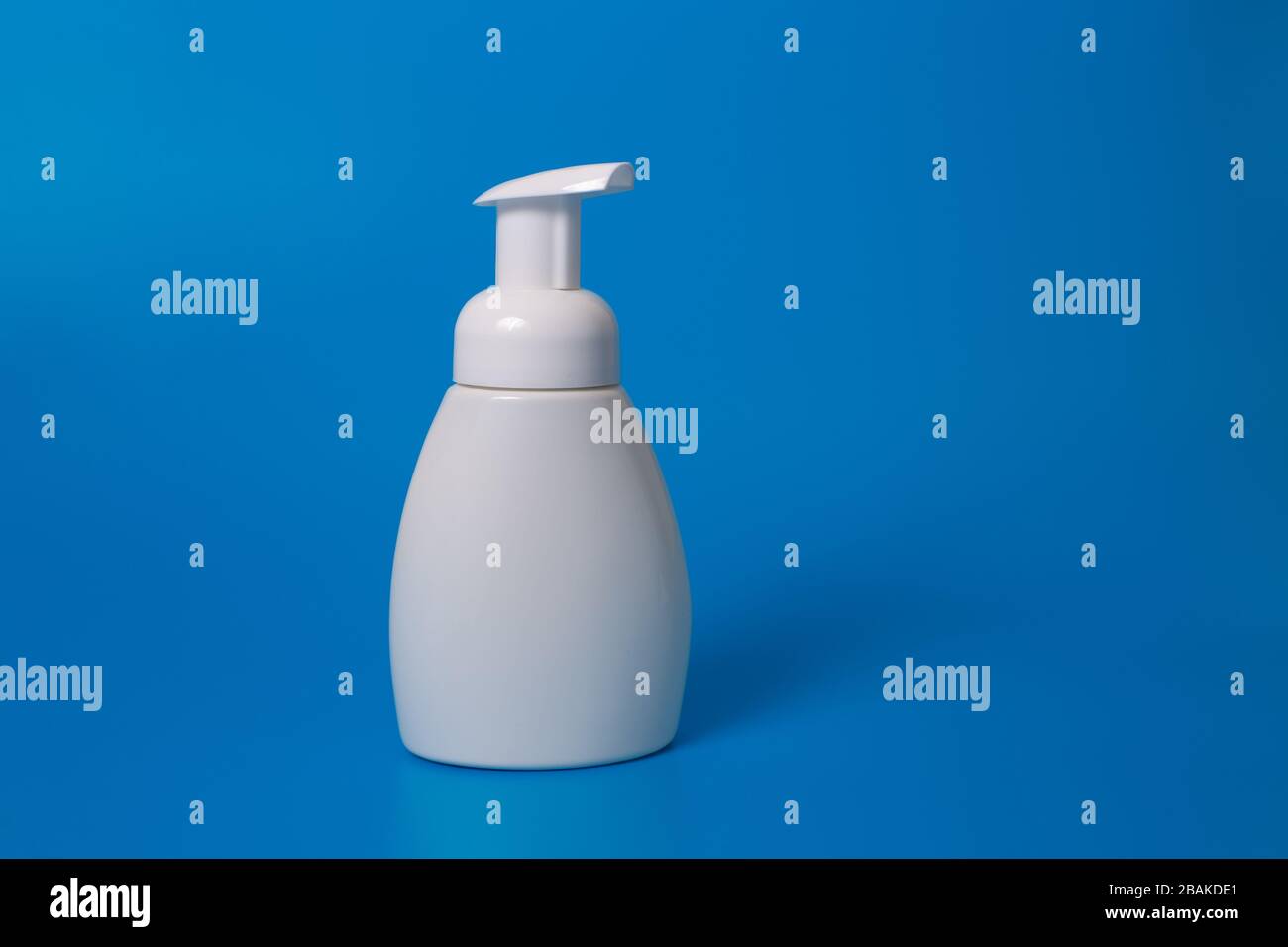 Weiße Flasche Flüssigseife auf blauem Hintergrund. Kopierbereich. Verspotten Sie sich Stockfoto