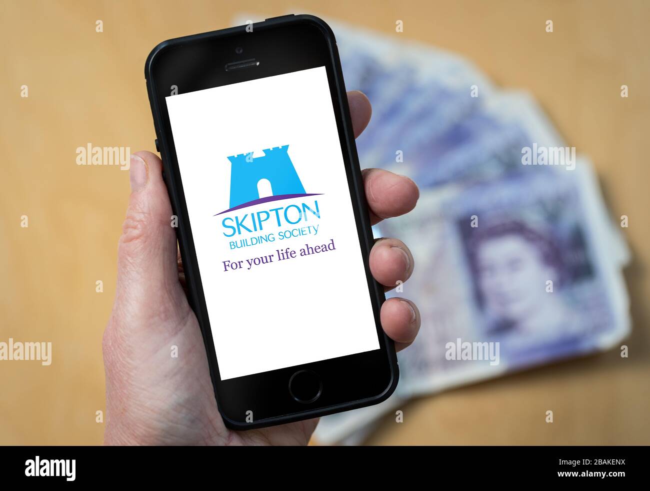 Eine Frau, die ein Mobiltelefon mit der Skipton Building Society hält (nur redaktionelle Verwendung) Stockfoto