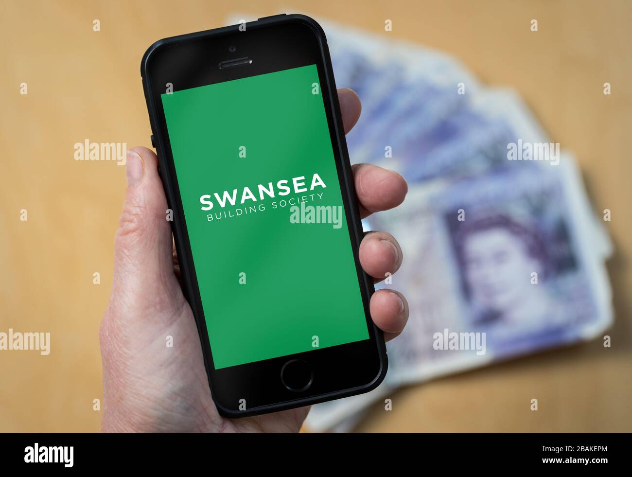 Eine Frau, die ein Mobiltelefon hält und die Swansea Building Society zeigt (nur redaktionelle Verwendung) Stockfoto