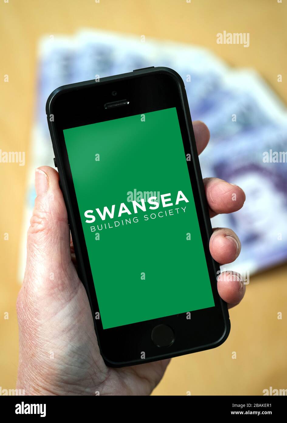 Eine Frau, die ein Mobiltelefon hält und die Swansea Building Society zeigt (nur redaktionelle Verwendung) Stockfoto