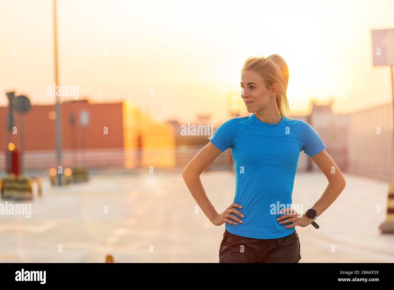 Junge Frau, die bei Sonnenuntergang auf Parkebene in der Stadt Fitnessübungen macht Stockfoto