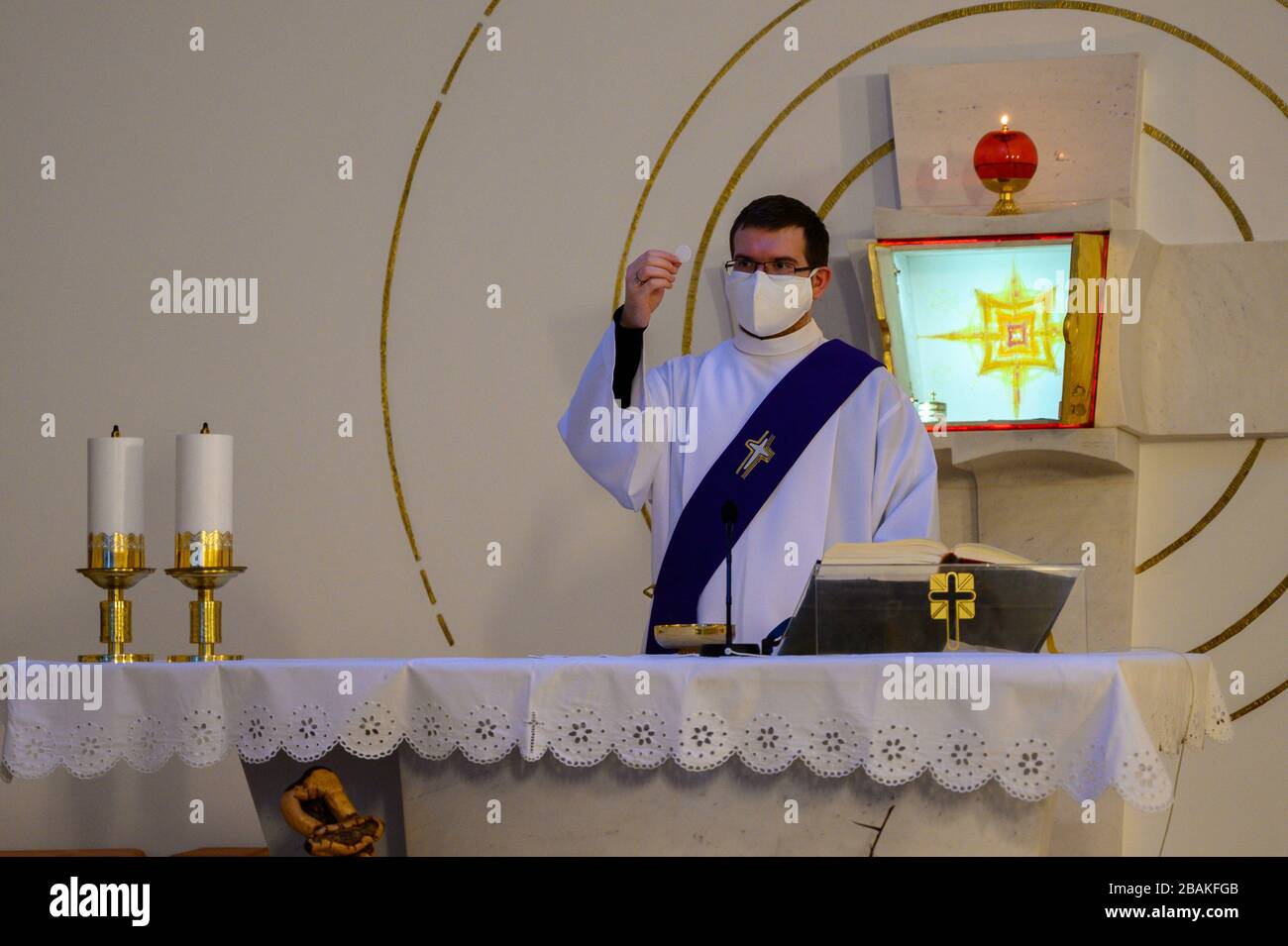 Bratislava, Slowakei. 2019/3/20. Ein Diakon, der die Hostie hält, bevor er die Eucharistie während der COVID-19-Pandemie an die Gläubigen in einer Kirche verteilt. Stockfoto