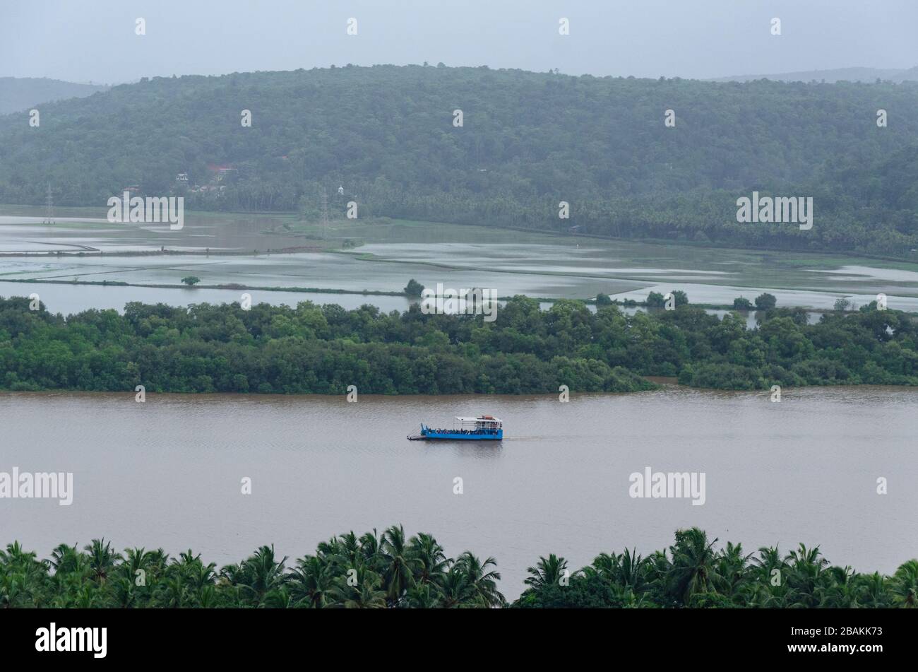 Schöne Aussicht auf Durbhat - Rassaim Fährschiff auf dem Zuari Fluss unter dunklen Monsunwolken, wie von Durbhat Hilltop, Ponda, Goa, Indien aus zu sehen Stockfoto