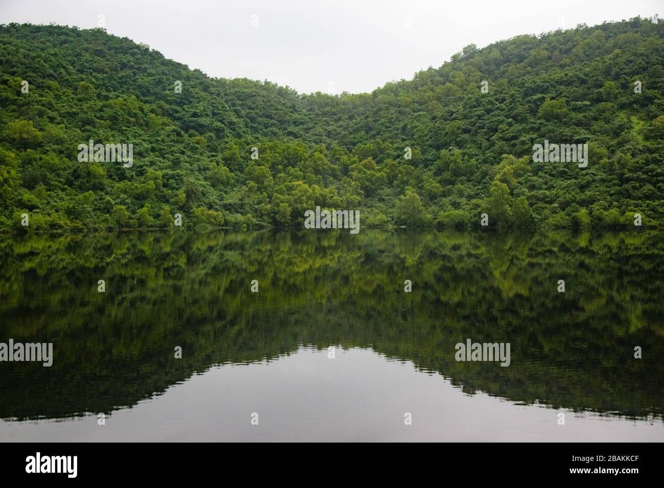 Stillgewässer des malerischen Sarzora-Sees in Salcete Taluka werfen ein nahezu perfektes Spiegelbild der benachbarten Berge. Stockfoto