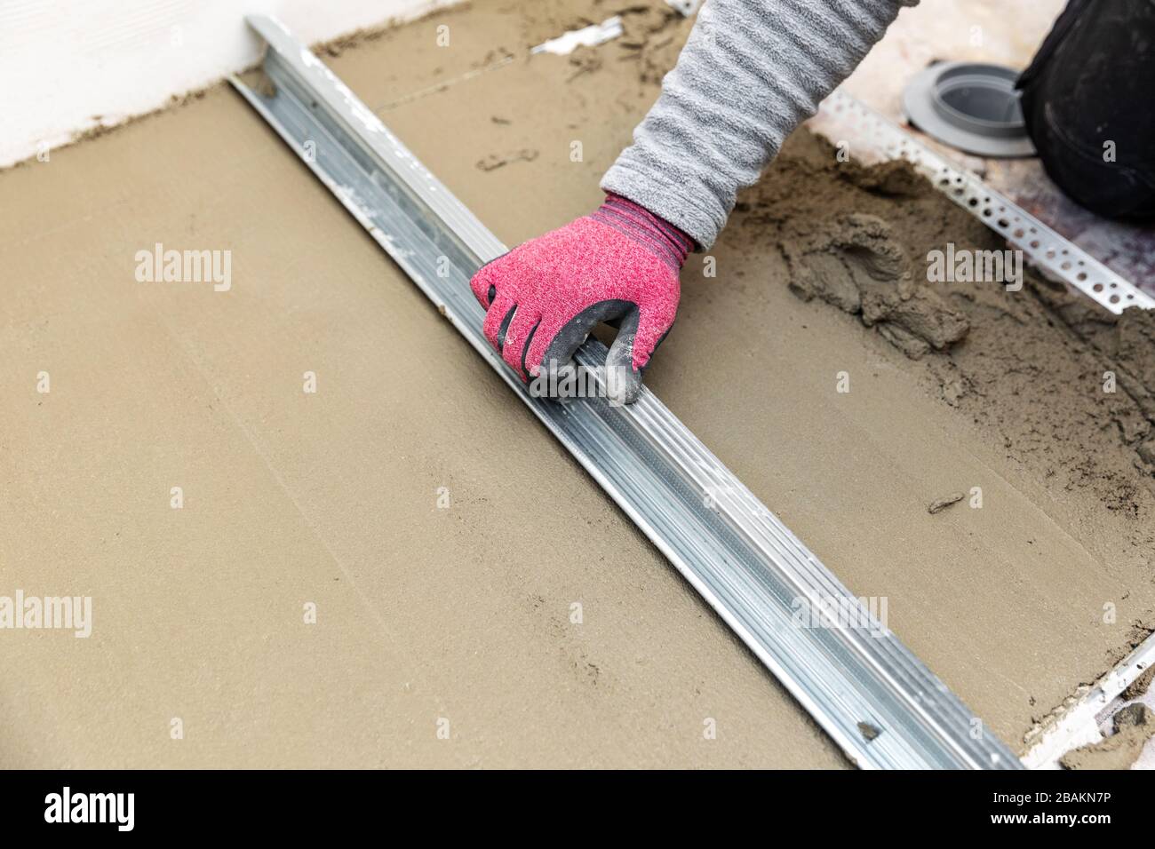 Der Bauarbeiter richtet den Betonboden aus Stockfoto