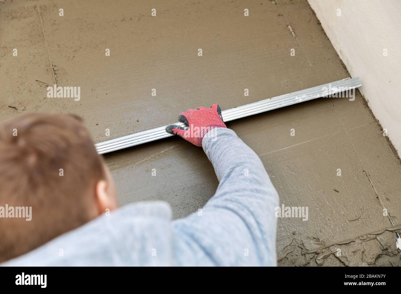 Der Bauarbeiter richtet den Betonboden aus Stockfoto