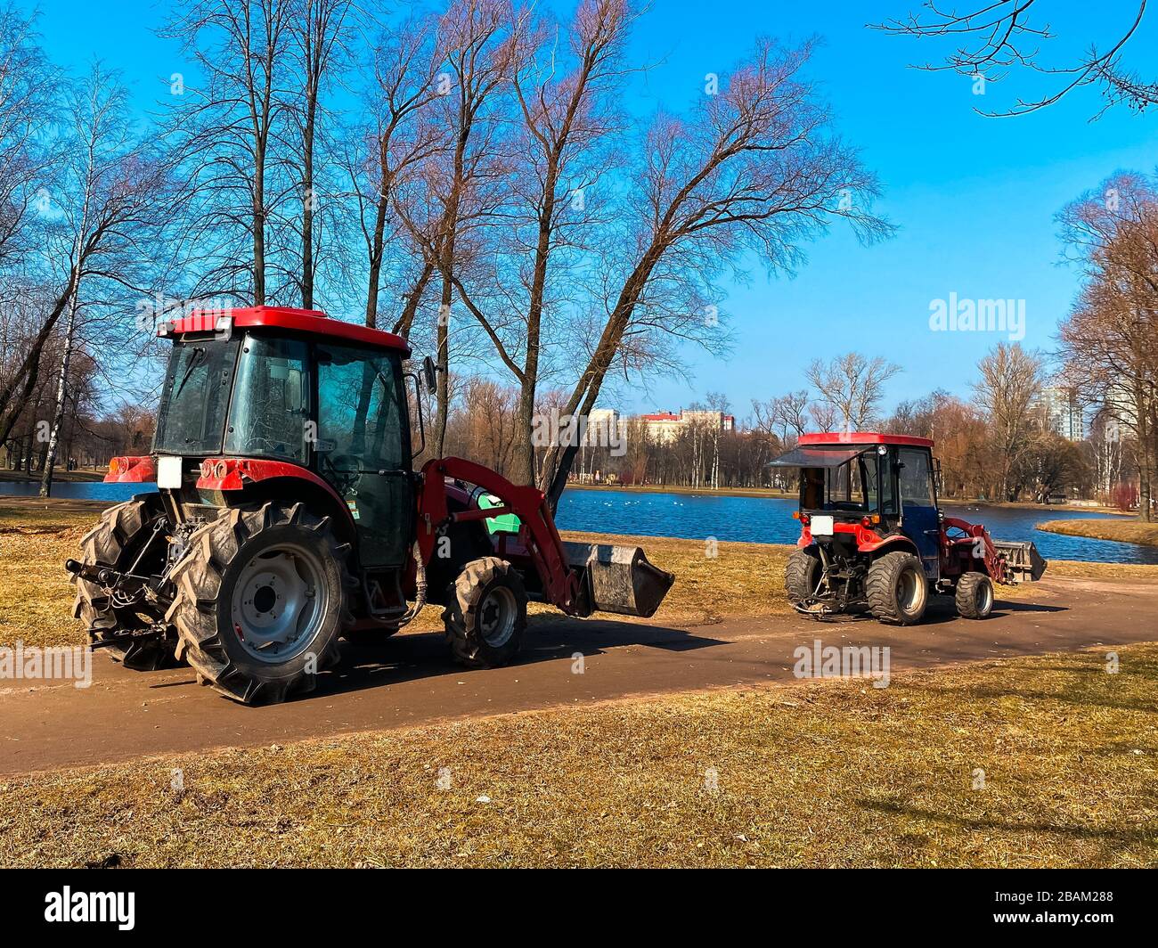 Rote Traktoren LKW im Frühling Stadtpark. Reinigung. Frühfrühling. Funktioniert. Sonniger Frühlingstag. Stockfoto