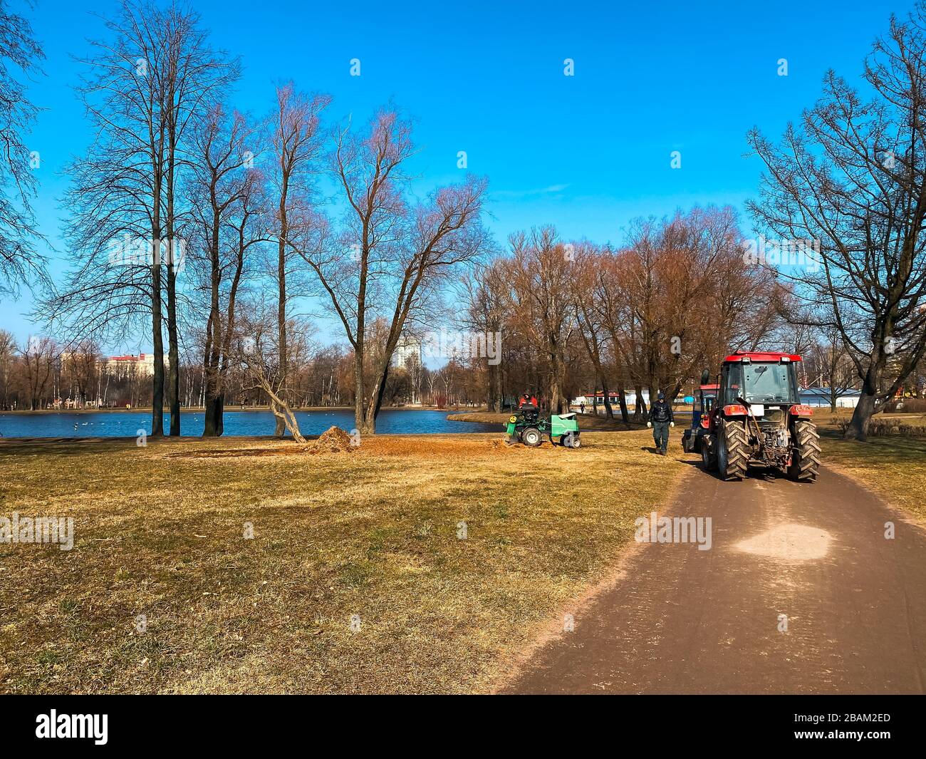 März, Sankt Petersburg, Russland. Rote Traktoren LKWs im Frühling Stadtparkreinigung. Frühfrühling funktioniert. Sonniger Frühlingstag Stockfoto