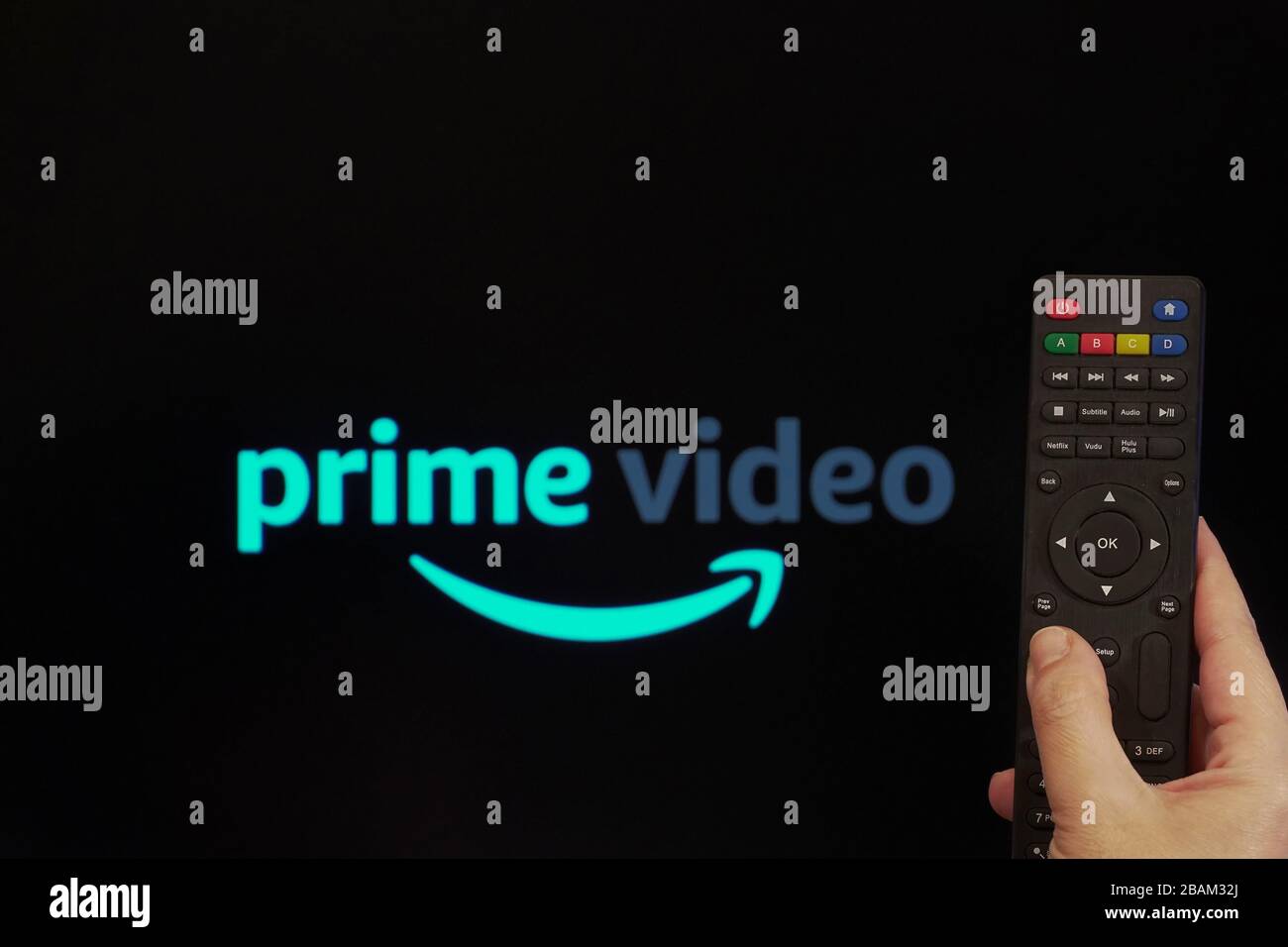 Amazon Streaming Service VoD Content Provider Konzept. Hand hält eine Multimedia-Fernbedienung vor einem Bildschirm mit dem Logo "Amazon Prime Video". Stockfoto