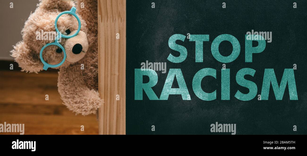 Halten Sie das Konzept von Rassismus und Kindern ein. Teddybär und ein Brett mit Stop Racism Text, Schulklasse Blackboard Hintergrund. Nein zur Botschaft des Rassismus für Kinder. Stockfoto