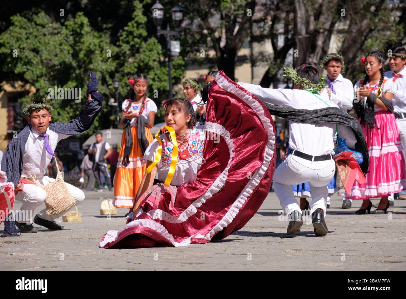 Junge mexikanische Paare folklorische Tänzerinnen, die traditionellen Tanz, in Bewegung in gekrockter Position ausführen Stockfoto