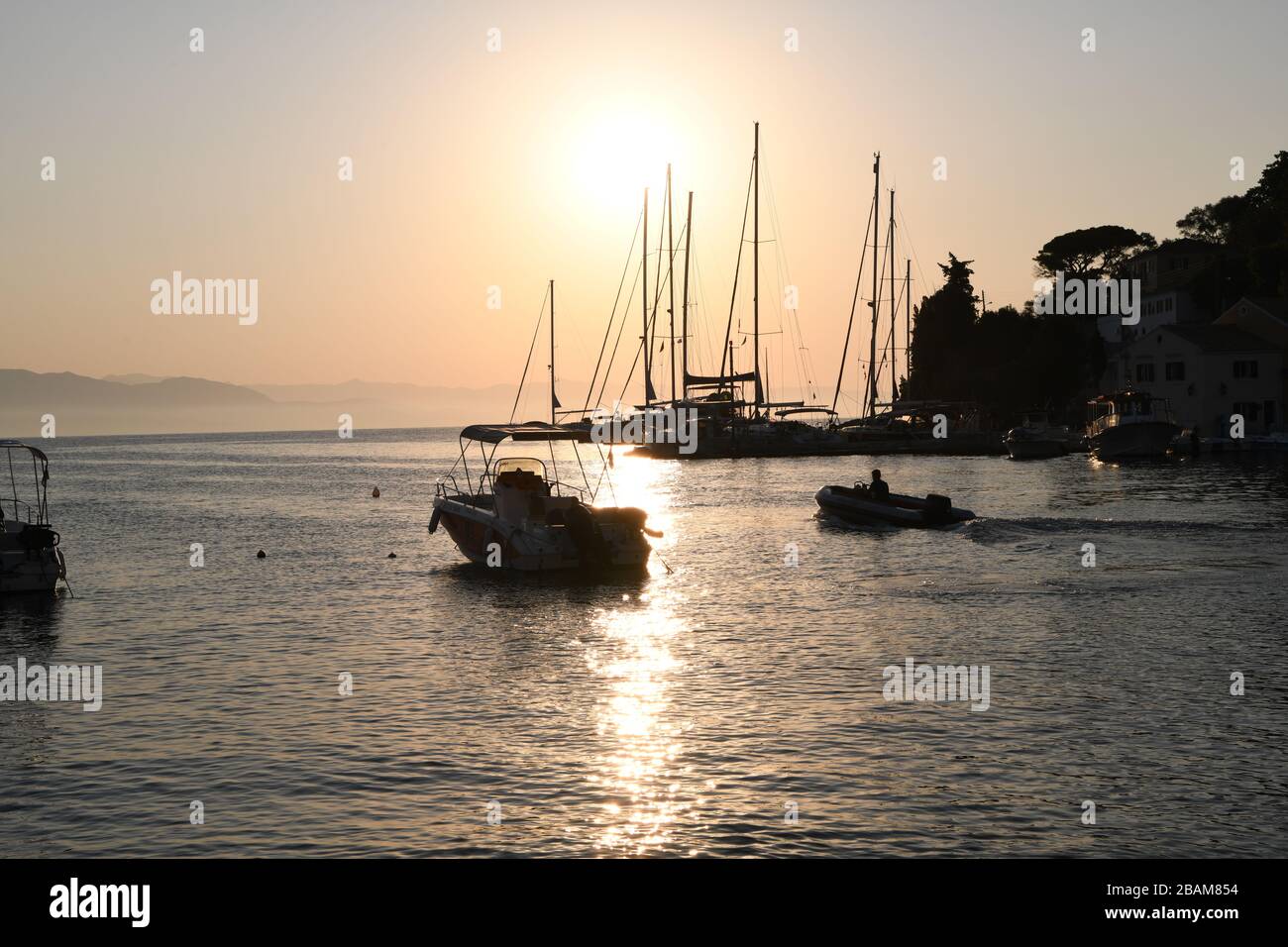 Sonnenaufgang über Segelbooten in Loggos, einem kleinen Fischerdorf an der Ostküste von Paxos (griechische Insel) Stockfoto