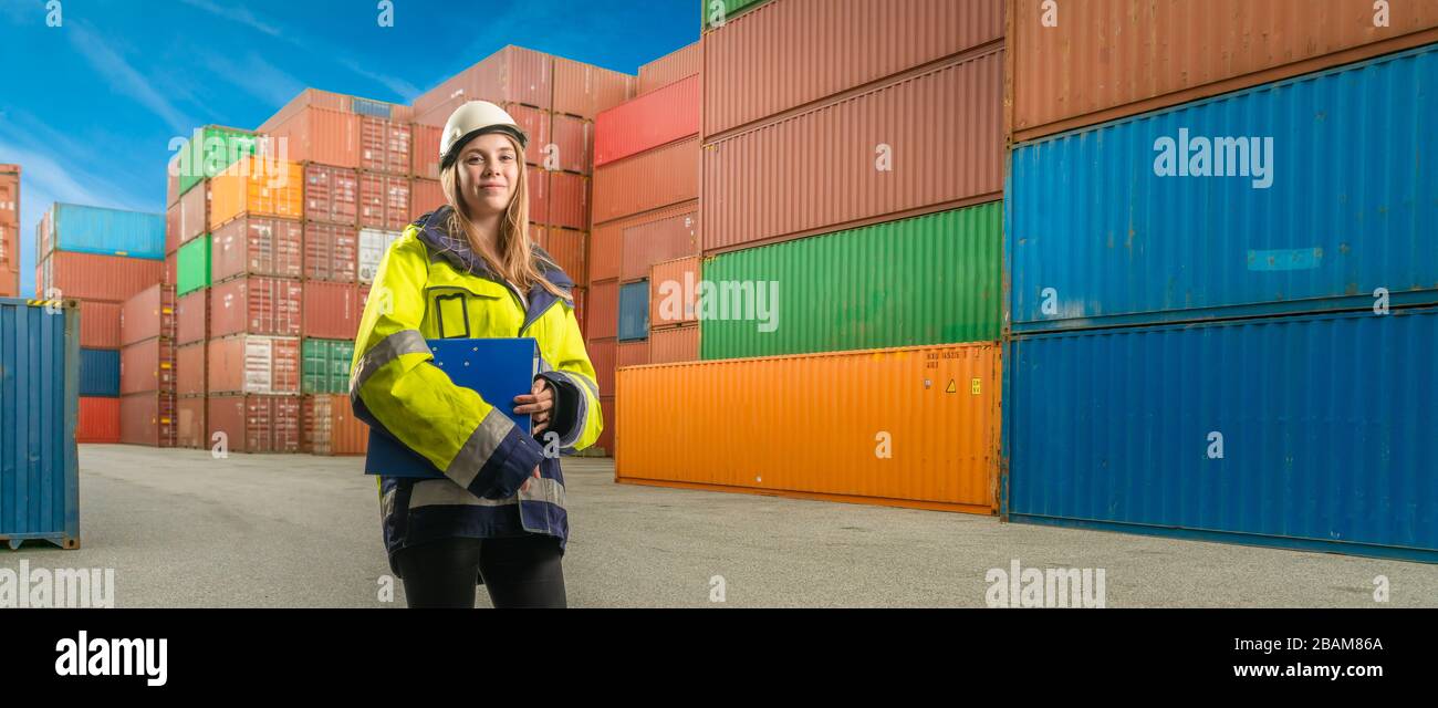 Eine lächelnde Hafenarbeiterin in einem Containertrminal Stockfoto