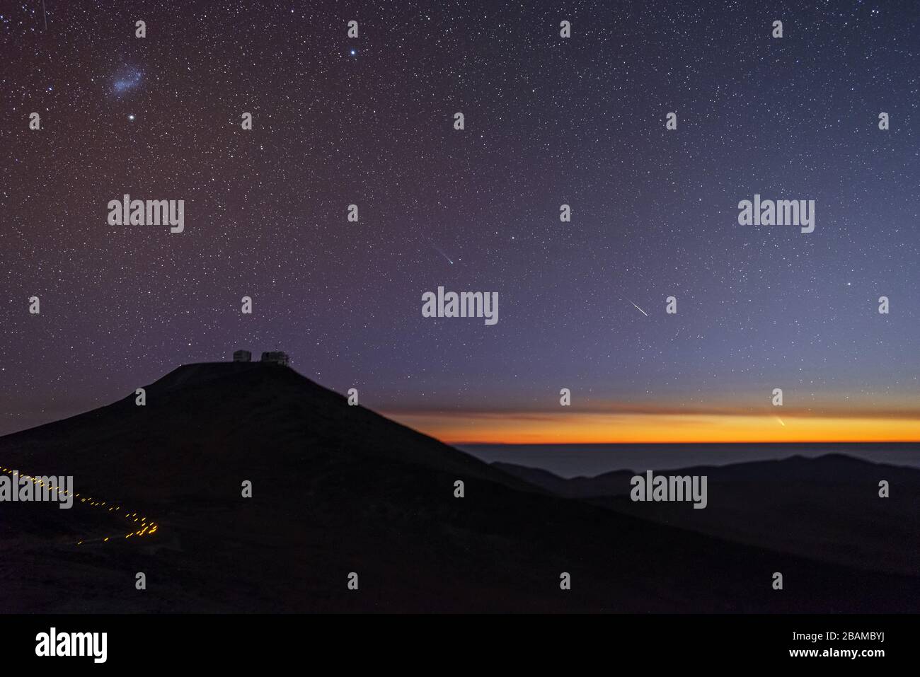 "Englisch: Dieses beeindruckende Bild wurde am 5. März 2013 von Gabriel Brammer, einem der ESO Photo Ambassadors, aufgenommen und zeigt einen Sonnenuntergang über dem Paranal-Observatorium mit zwei Kometen, die sich derzeit über den südlichen Himmel bewegen. In der Nähe des Horizonts, auf der rechten Seite des Bildes, zeigt Comet C/2011 L4 (Pan-STARRS), der hellste der beiden, einen hellen Schwanz, der hauptsächlich durch Staub verursacht wird, der das Sonnenlicht reflektiert. Im Zentrum des Bildes, knapp über den rechten hängen des Cerro Paranal, liegt das grünliche Koma - eine nebulöse Hülle um den Zellkern - von Comet C/2012 F6 (Lemmon) Ca Stockfoto