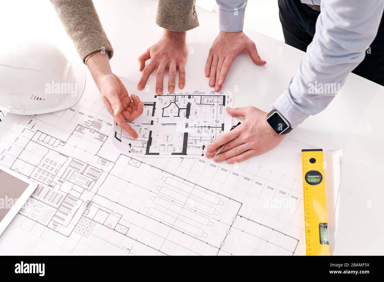 Über der Ansicht, dass nicht erkennbare Unternehmer auf einen flachen Plan zeigen, während sie mit dem Architekten darüber sprechen Stockfoto