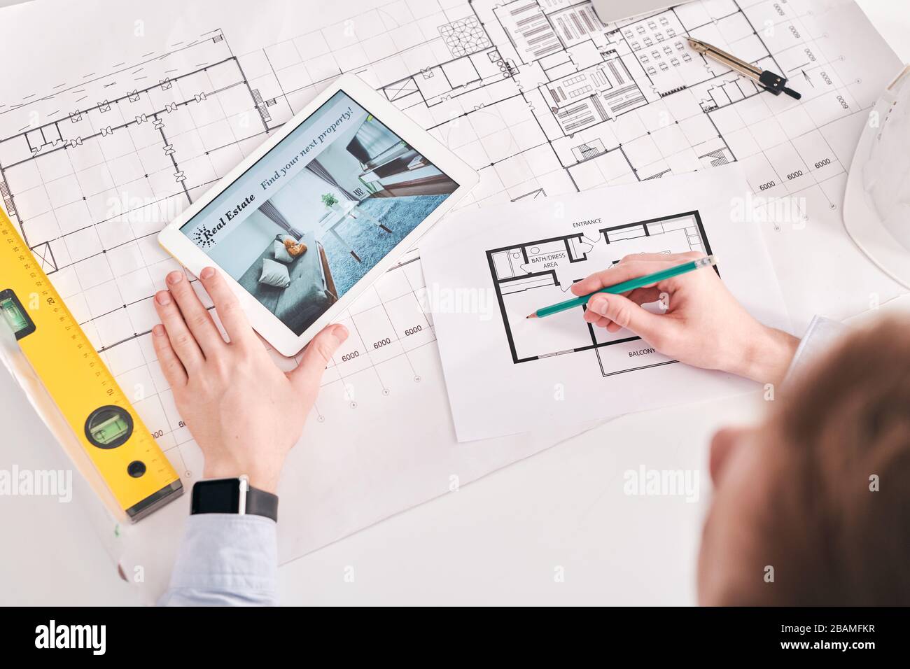 Über der Ansicht des Architekten mit digitalen Tabletts und Blaupausen bei der Arbeit auf dem Grundriss der Wohnung Stockfoto