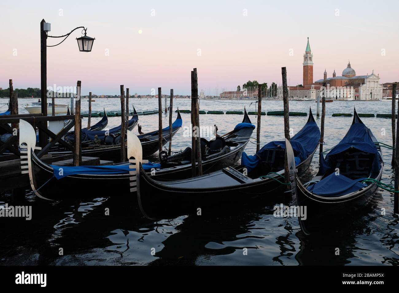 Eine Reihe angedockter Gondeln bei Sonnenuntergang in Venedig. Stockfoto