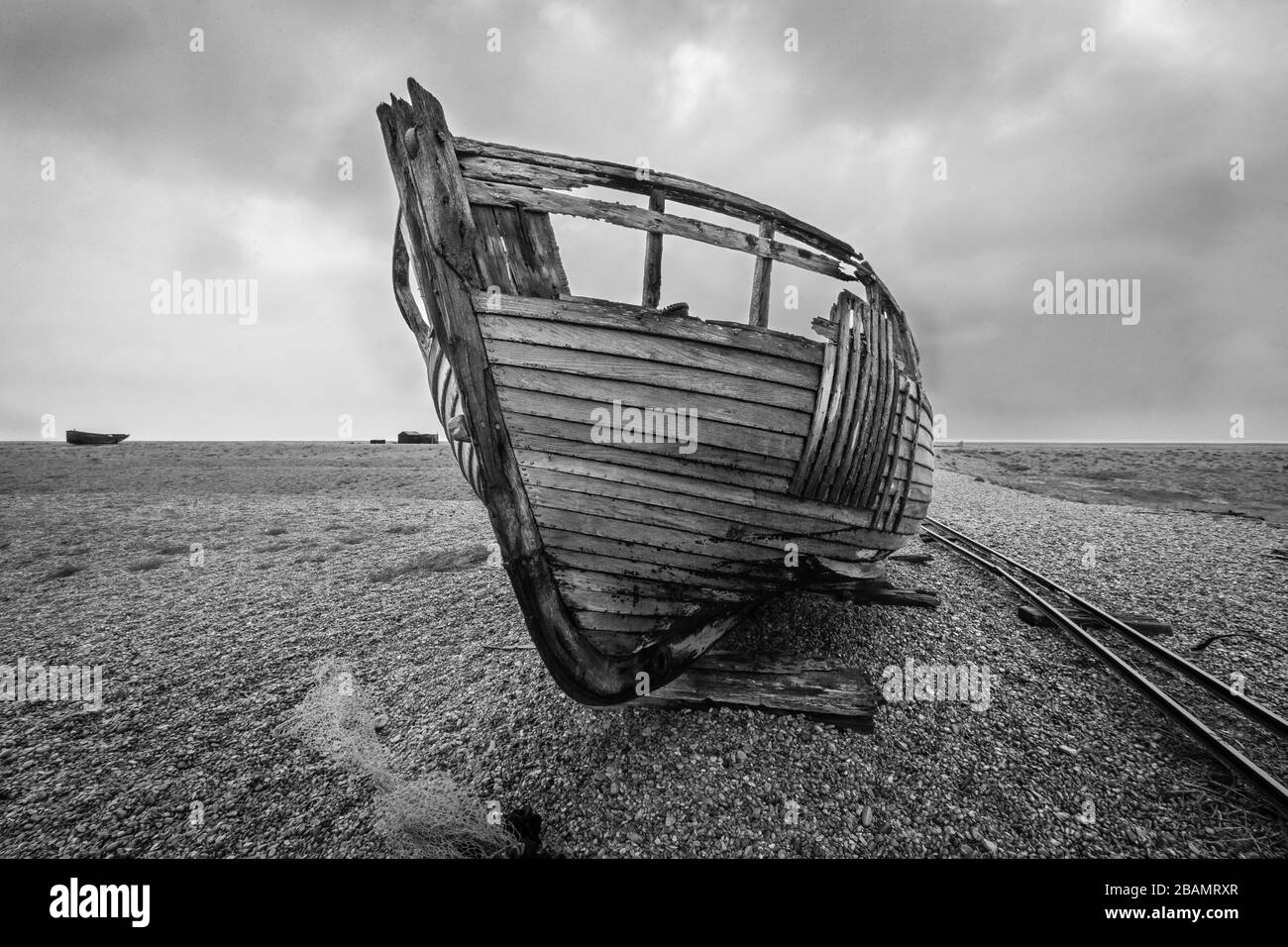 Ein Boot auf dem verlassenen Dungeness Beach in England, wo ein verfallener Weltmenschen zurückblieb. Spektakulär krass und kompromisslos, aber auch schön. Stockfoto