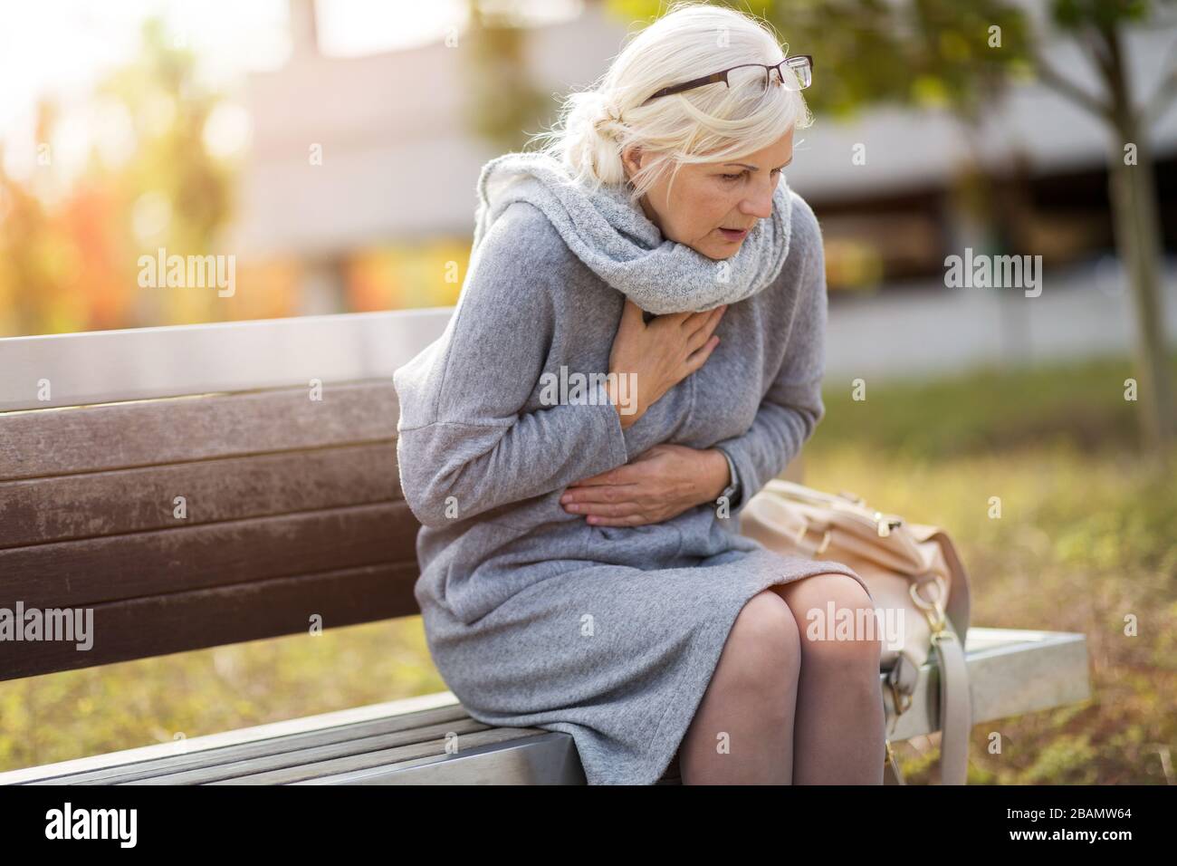 Ältere Frau, Die Unter Schmerzen Leidet, Während Sie Auf Der Bank Sitzt Stockfoto