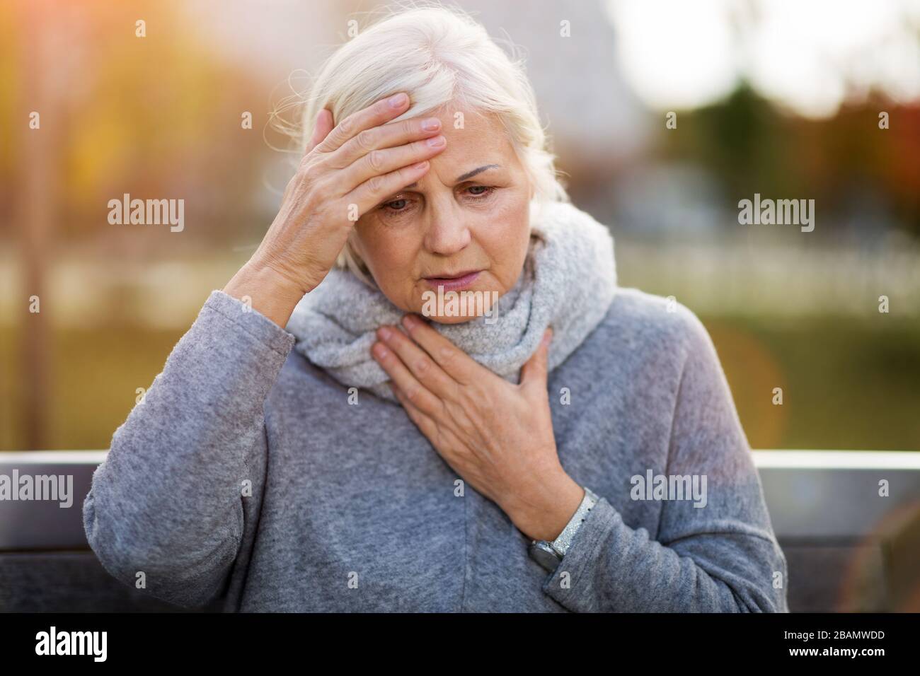 Ältere Frau, Die Unter Schmerzen Leidet, Während Sie Auf Der Bank Sitzt Stockfoto