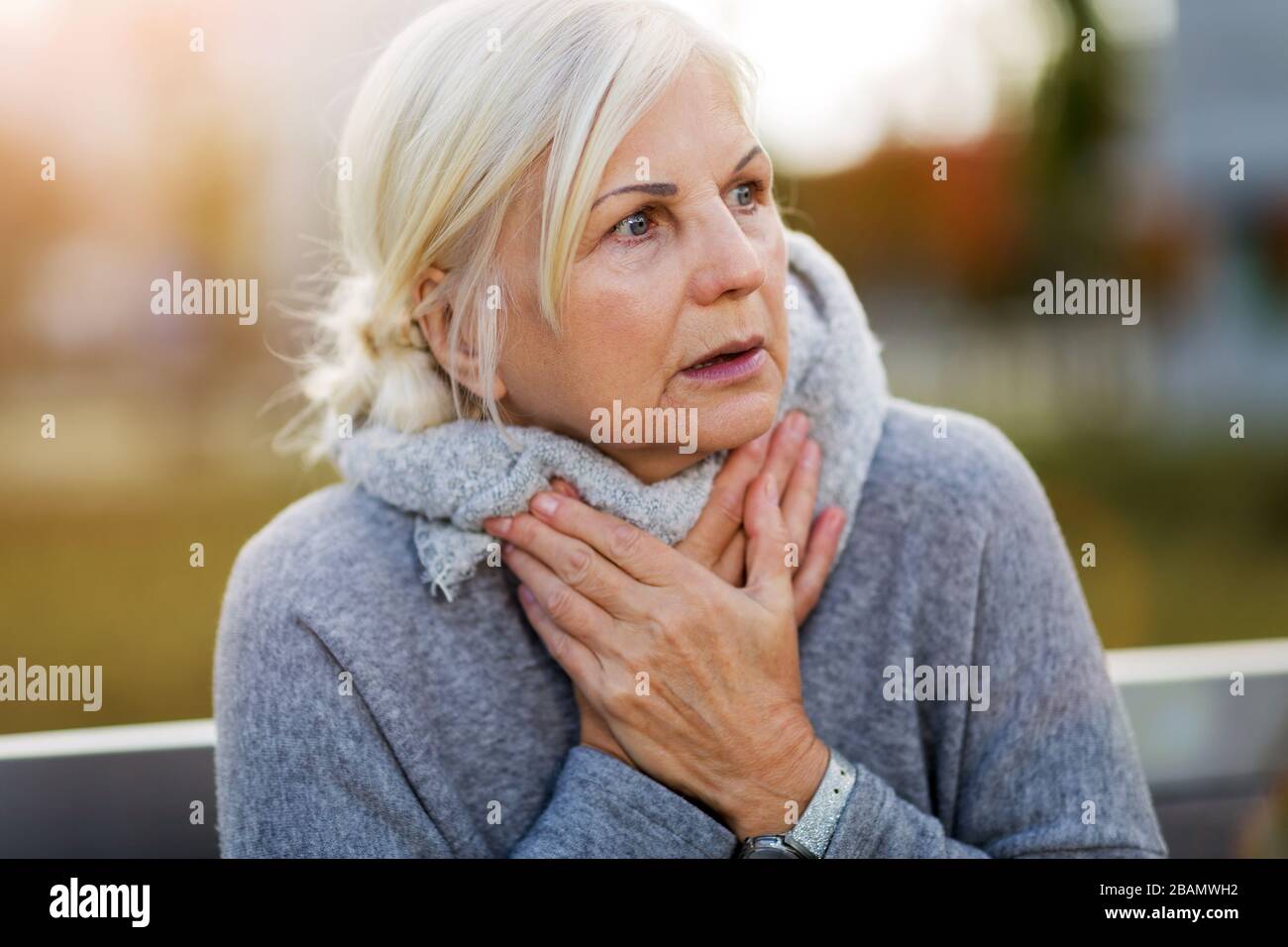 Ältere Frau, Die Unter Schmerzen Leidet, Während Sie Auf Der Bank Sitzt Stockfoto