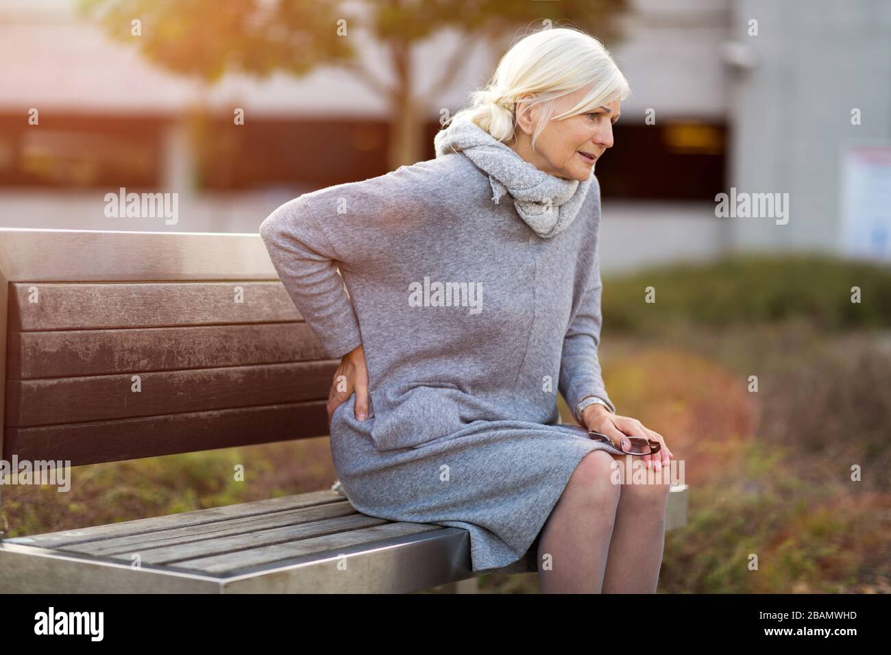 Ältere Frau, Die Unter Schmerzen Leidet, Während Sie Auf Der Bank Sitzt Stockfoto