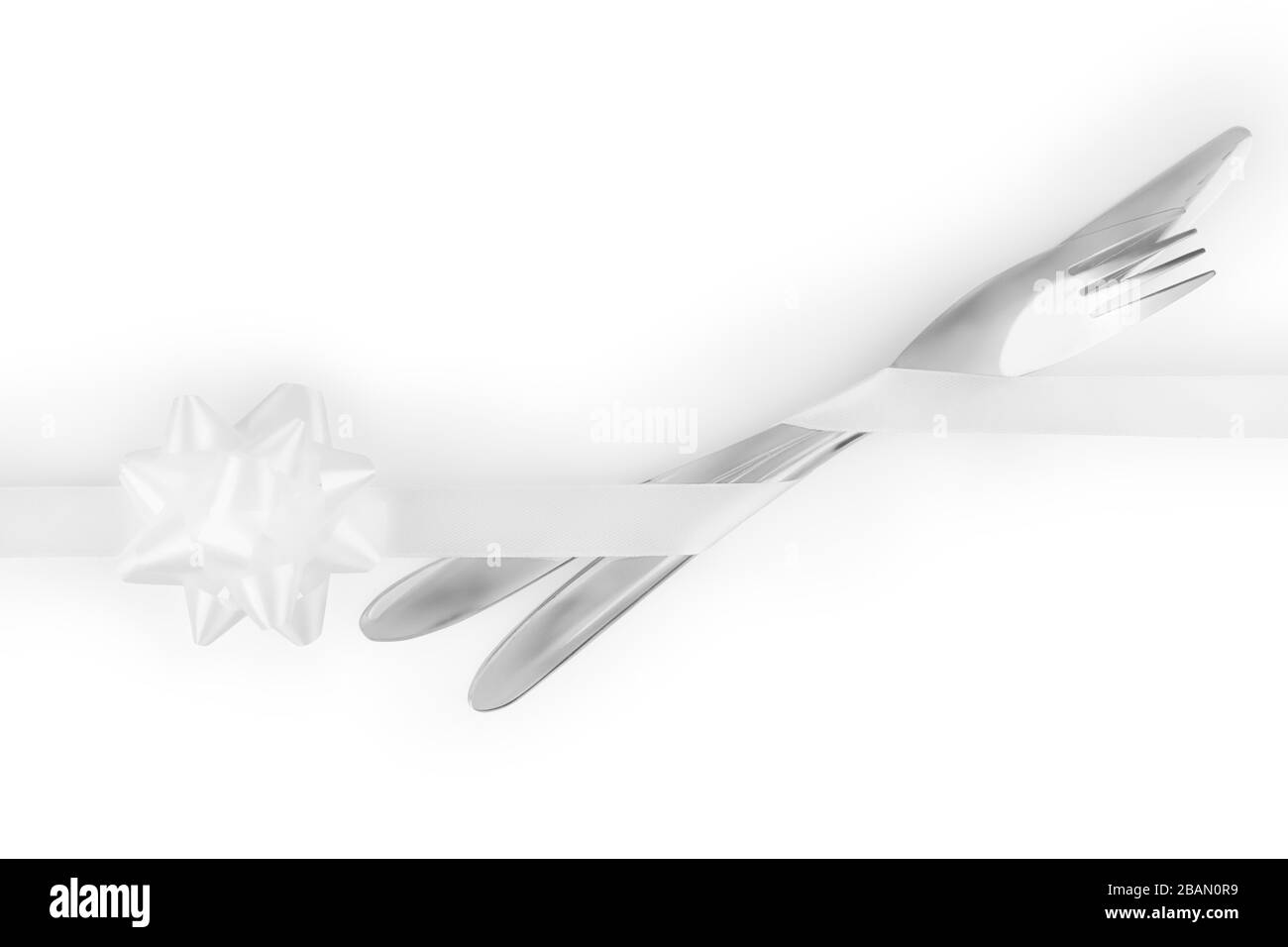 Gabel und Messer mit einem weißen Band mit geknallter Schleife, isoliert auf weißem, Schneideweg enthalten Stockfoto