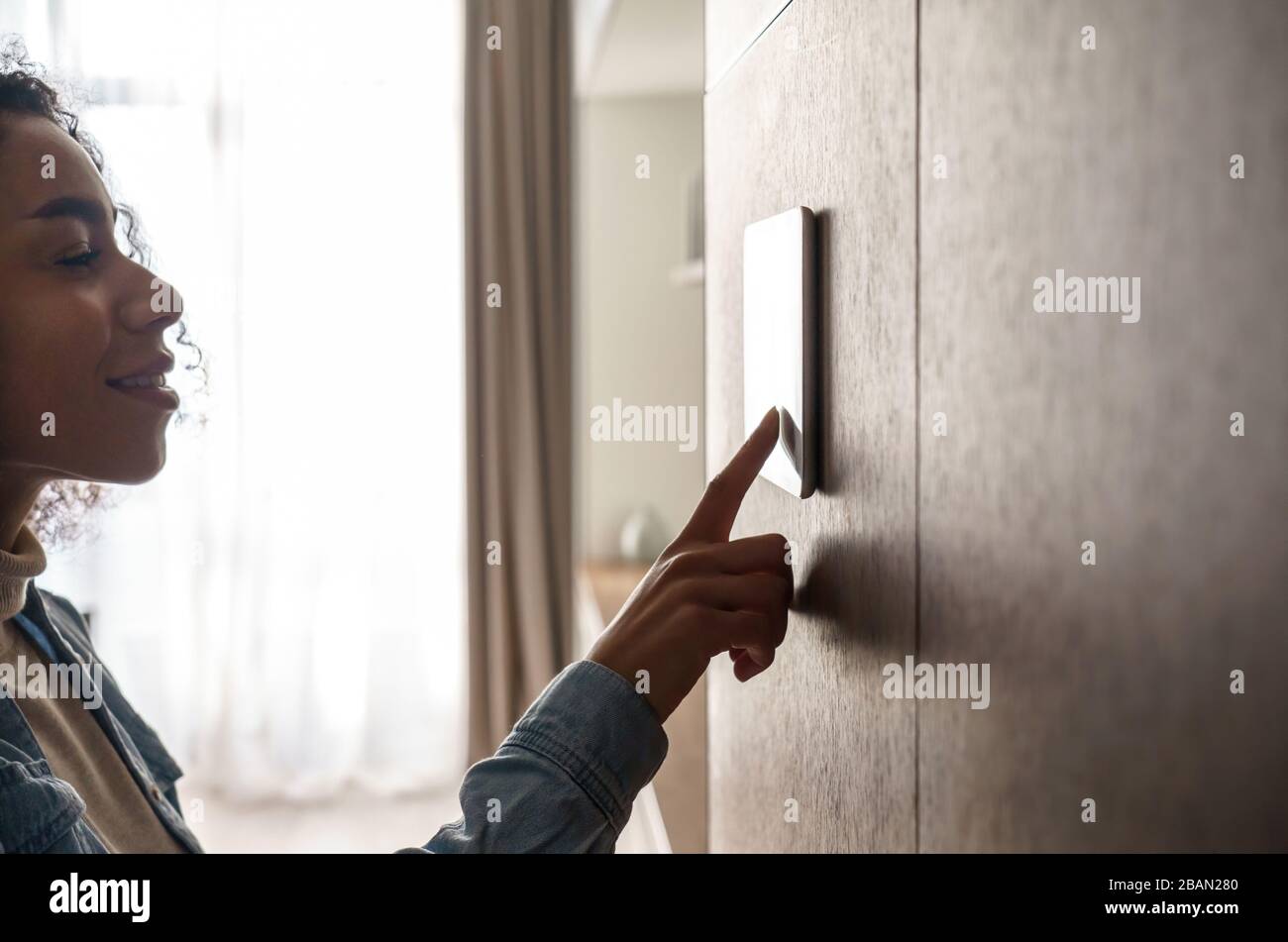 Afrikanerin mit intelligentem Touchscreen-Gerät an der Wand. Stockfoto