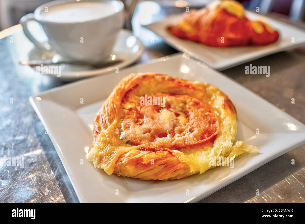 Tomaten-Tart-Blätterteig zum Frühstück mit Käse und einer Tasse Lettenkaffee. Stockfoto