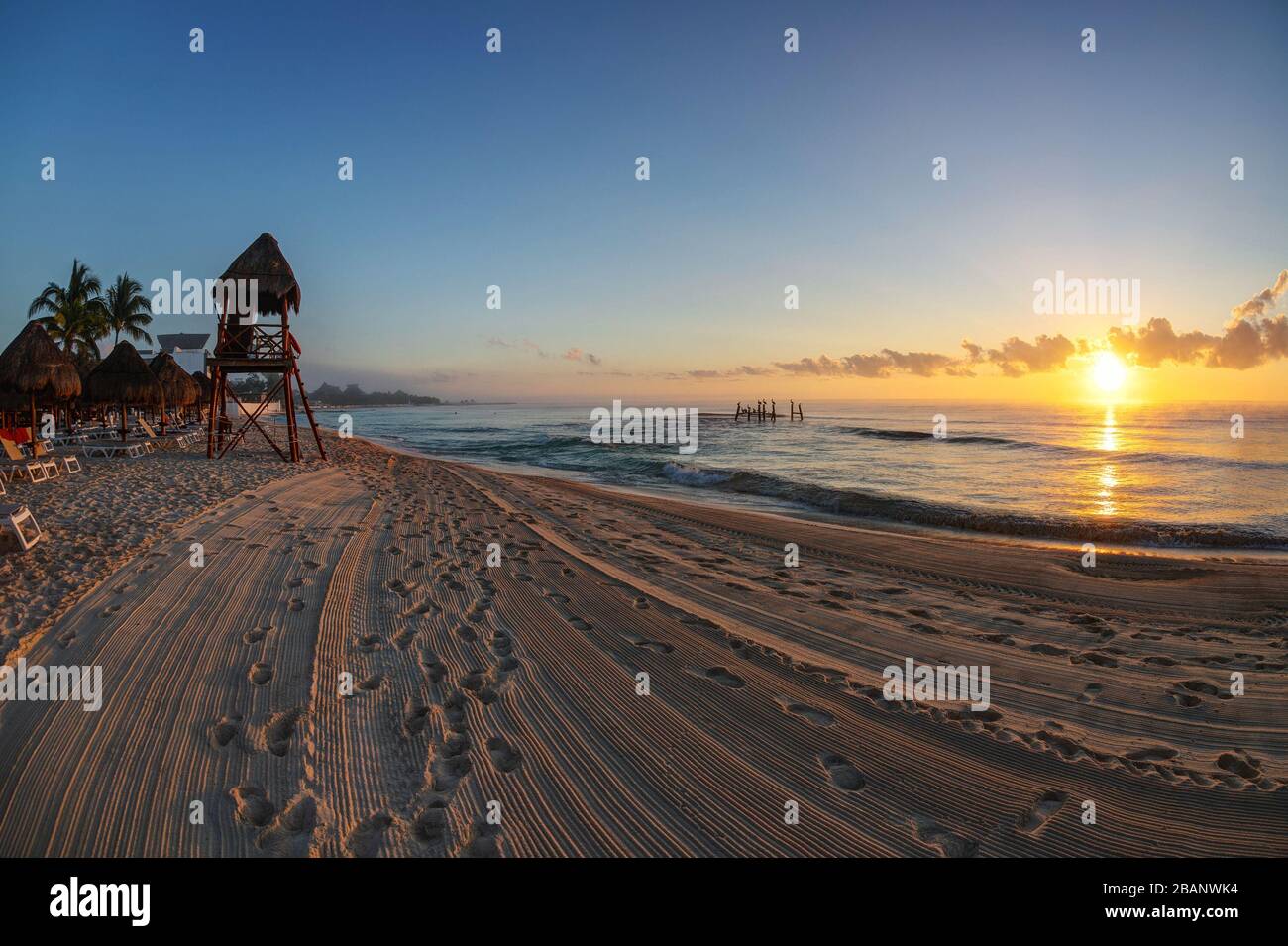 Goldener Sonnenaufgang über den tropischen Stränden der Riviera Maya in der Nähe von Cancun, Mexiko, mit Badehausturm mit Blick auf das karibische Meer. Stockfoto